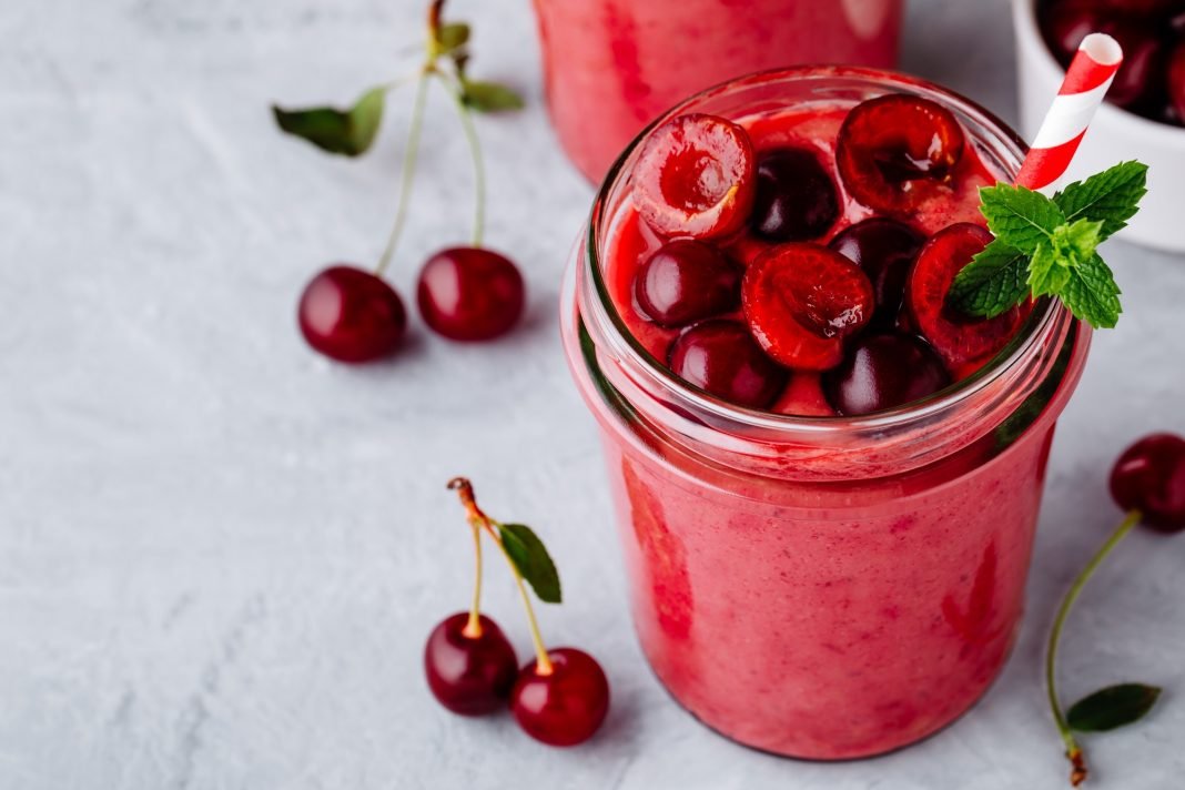 Cherry smoothie in glass with mint leaves and fresh berries